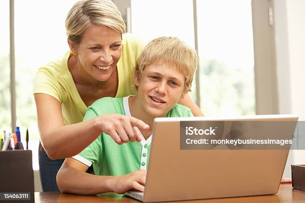 Mother Helping Her Teenage Son On The Laptop Stock Photo - Download Image Now - 30-39 Years, Adult, Assistance