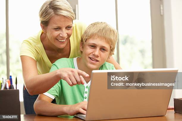 Mãe E Filho Adolescente Usando Computador Portátil Em Casa - Fotografias de stock e mais imagens de 30-39 Anos