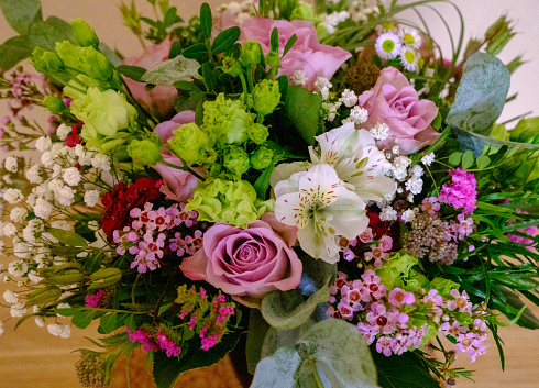 Colorful bouquet of different fresh flowers. A bunch of orchids, roses, freesia and eucalyptus leaves. Rustic floral background. View from the top.