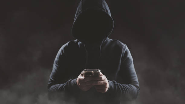 istock Hacker wear hood holding smartphone with red warning icon to launch ransomware malware attack on victim 1540681030
