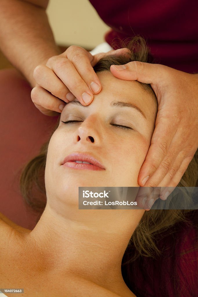 Close-up of woman receiving pressure point massage a good looking woman receives a massage of her chiropractor on her forehead 20-29 Years Stock Photo