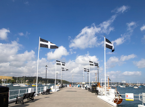 Falmouth, Cornwall, UK - July 2023: Cornish flags flying on the Prince of Wales pier in Falmouth, Cornwall, UK