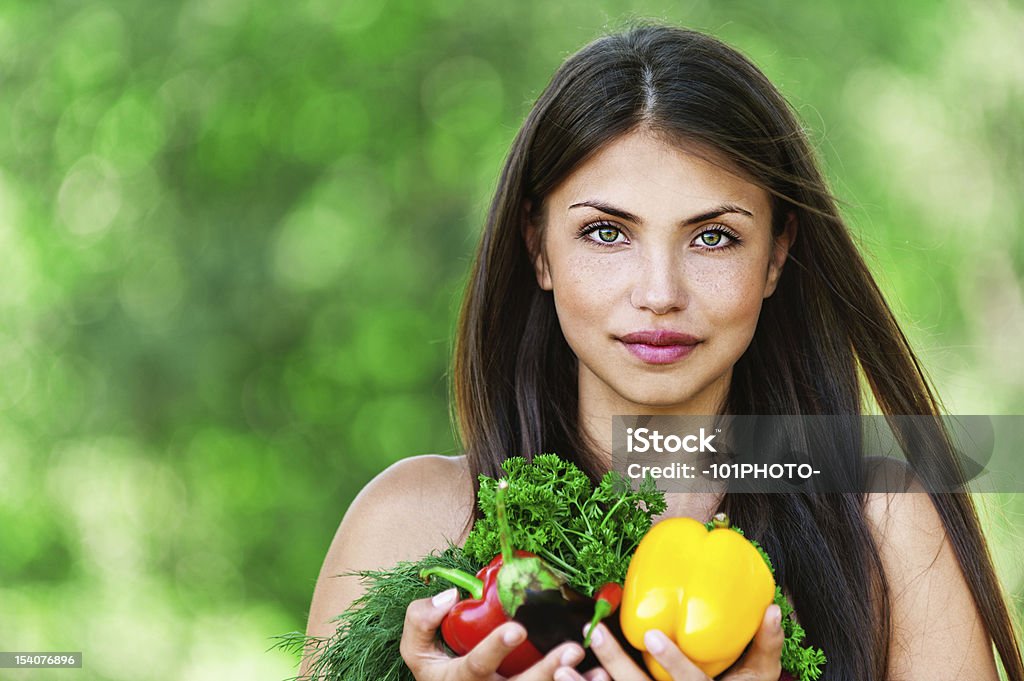 girl with vegetarian set portrait of beautiful dark-haired smiling girl set with vegetables and herbs (eggplant, Bulgarian pepper red and yellow, dill and parsley) in hands on green background Adult Stock Photo