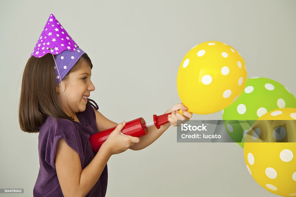 Inflating balloons A kid isolated inflating vibrant balloons with an air pump for her birthday party. Adolescence Stock Photo