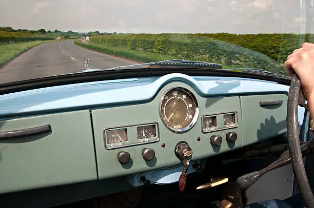A rare classic open topped British car being driven along a country road in Somerset.