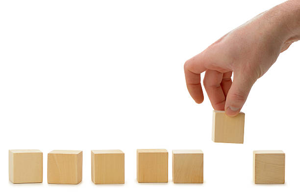 The hand establishes a wooden cube in row stock photo