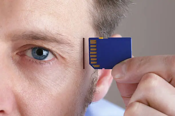 Inserting SD memory card into slot in human head concept for memory upgrage, forgetfulness or computing