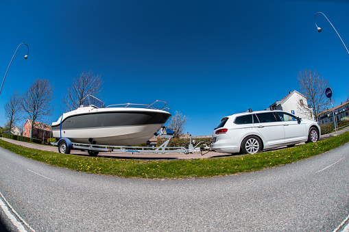 Gothenburg, Sweden - May 05 2023: Wide angle photo og a white car and boat on a trailer.