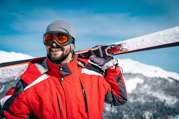 istock Happy athletic man wearing ski goggles while looking away with skies on a shoulder 1540865830