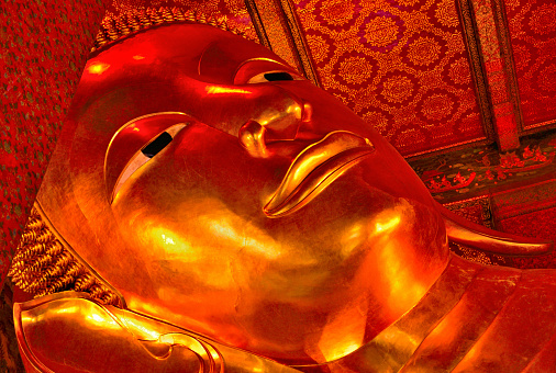 Reclining Buddha image at Wat Pho in gold and decorated in red to make it look even more exotic, Bangkok, Thailand