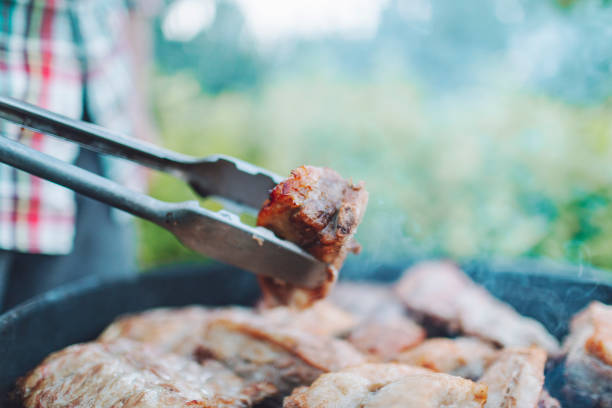 Young adult man grilling pork ribs for 4th of July celebration