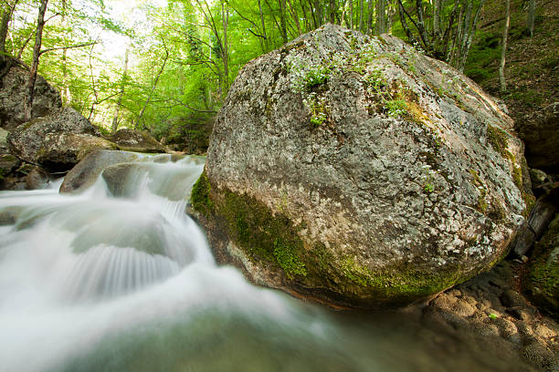 river in mountains and big boulder stock photo