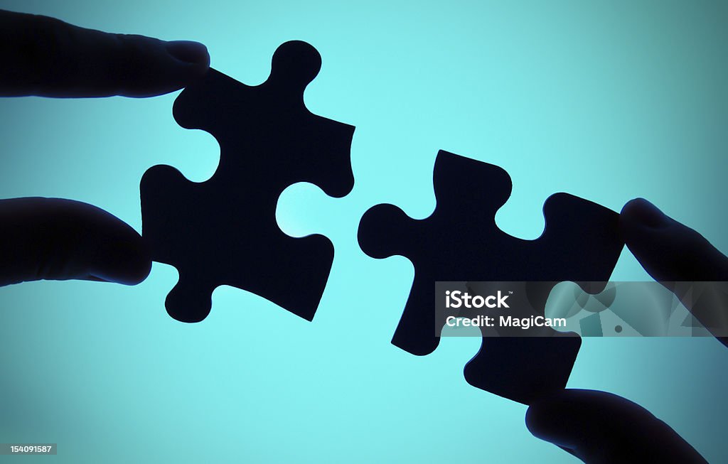 connecting two pieces of puzzle two hands connecting two pieces of puzzle Blue Stock Photo