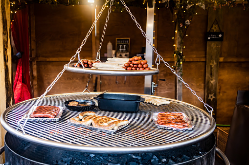 Grilling sausages on barbecue grill at a food stall of Christmas market