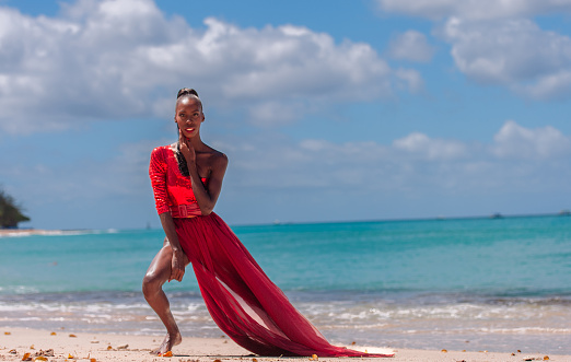 Woman Wearing Red Bikini and Dress on a tropical beach. Remote tropical beach in Barbados, Caribbean Sea. Black. Portrait.