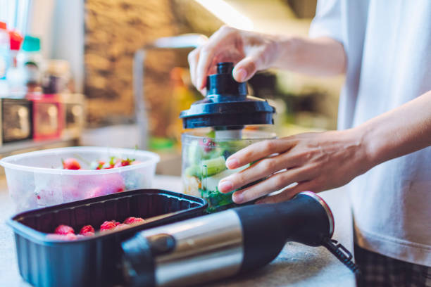istock Young adult woman making smoothie for breakfast using blender 1540970693