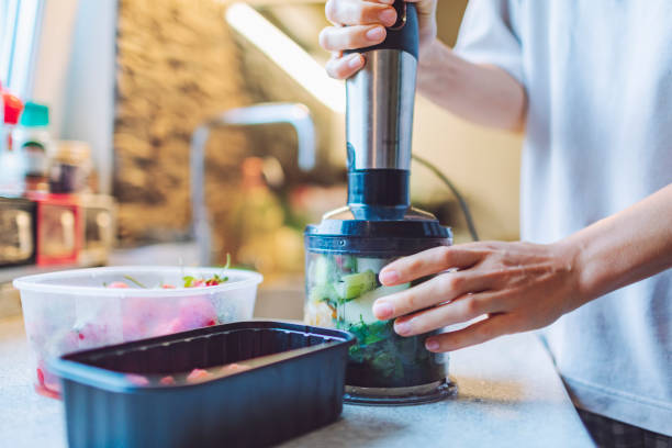istock Young adult woman making smoothie for breakfast using blender 1540970694