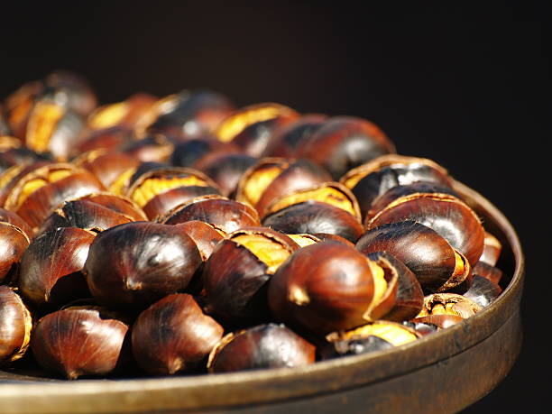 hot castañas sobre fondo negro. - chestnut roasted heat roasted chestnut fotografías e imágenes de stock