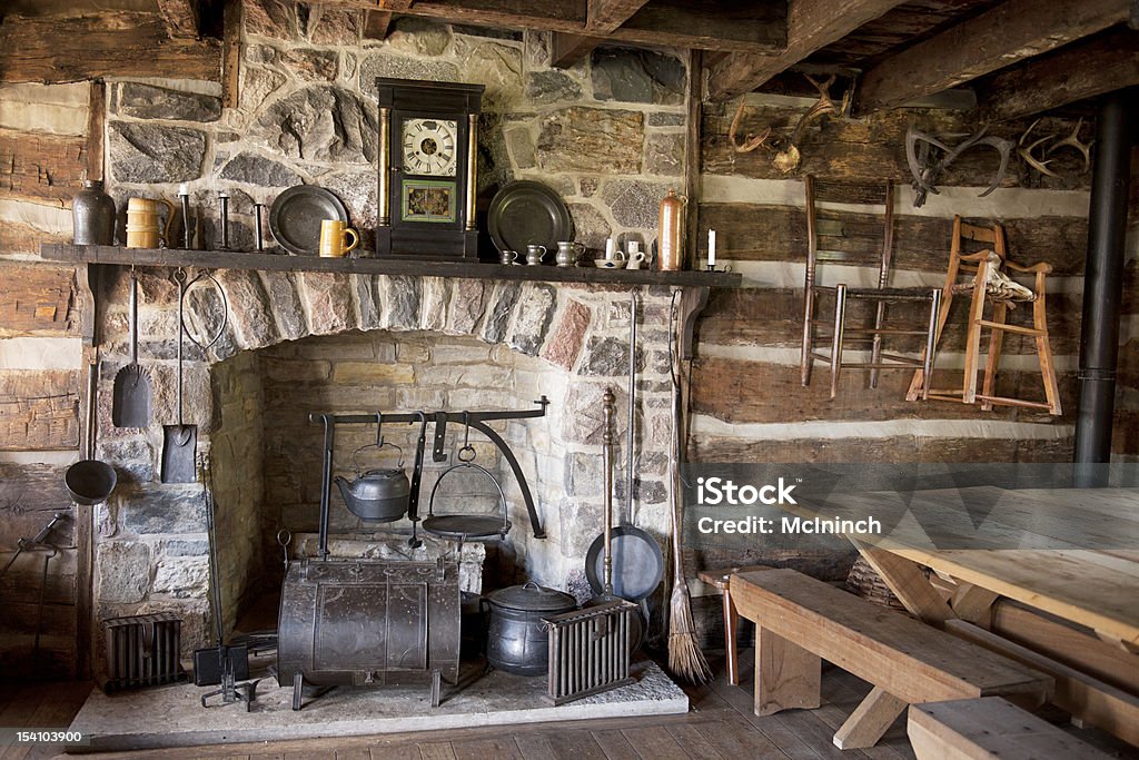 Pioneer Living Room The fireplace and utensils of an old pioneer log home. Log Cabin Stock Photo
