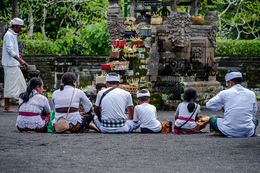 Bali, Indonesia--Feb 28, 2023--Family offers prayers in the inner sanctum of the Taman Ayun Temple.