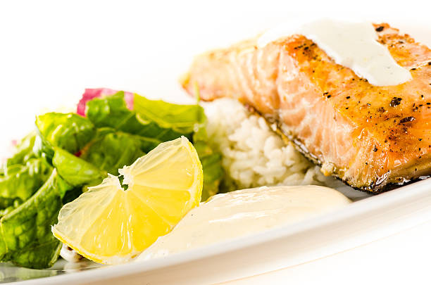 istock baked salmon with rice, side salad, sauce and lemon wedge 154106300