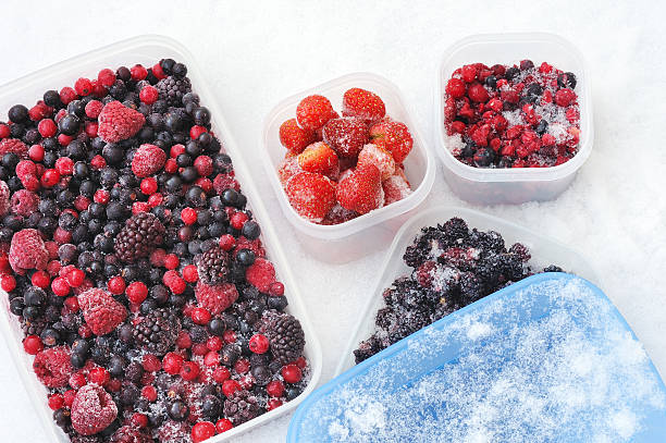 Plastic containers of frozen mixed berries in snow stock photo