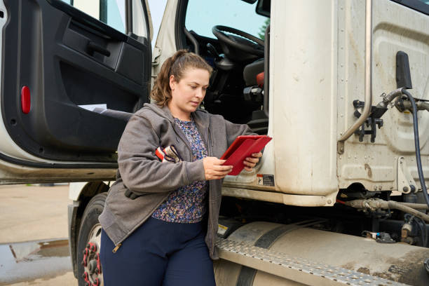 istock Female trucker driver checking routes on a tablet while leaning on her truck 1541209849