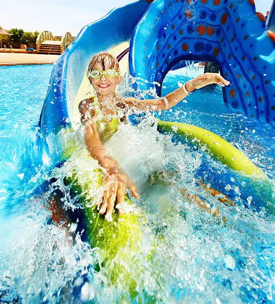 Child on water slide at aquapark. Summer holiday.