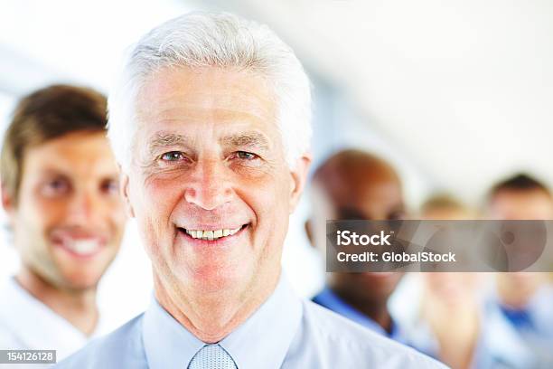 Geschäftsmann Lächelnd Mit Kollegen Im Hintergrund Stockfoto und mehr Bilder von Aktiver Senior - Aktiver Senior, Alter Erwachsener, Arbeitskollege