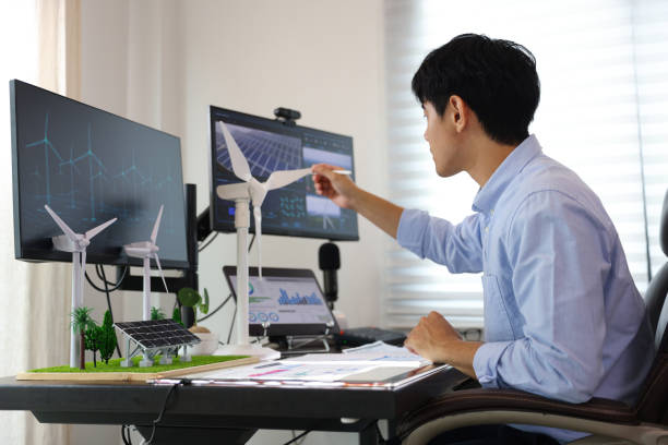 istock Close-up side view of the Mechanical Engineer Designing 3D wind turbine model on a personal computer. Professional working at the office, Concept models of buildings and wind turbines on a desk in the office 1541268034
