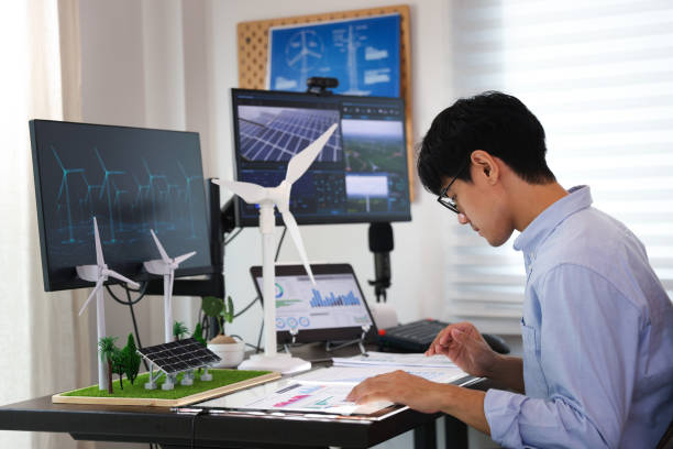 istock Close-up side view of the Mechanical Engineer Designing 3D wind turbine model on a personal computer. Professional working at the office, Concept models of buildings and wind turbines on a desk in the office 1541268035