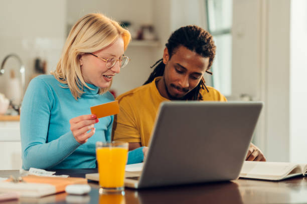 istock A happy multicultural couple is sitting at their home and using a credit card for paying bills and taxes online on the laptop. 1541322738