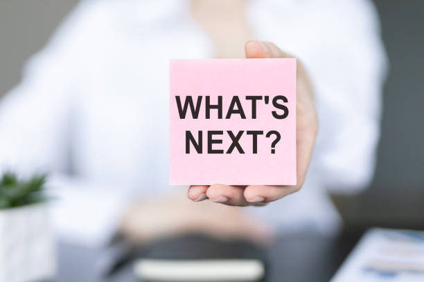 Hand showing the text WHAT'S NEXT, text on paper sticker