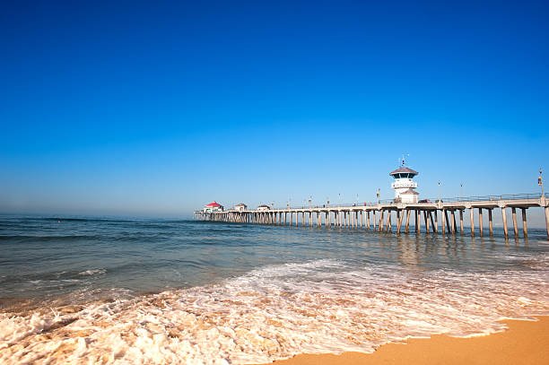 Huntington Beach Pier during early morning shows the tides changing with rushing surf moving up the shoreline.