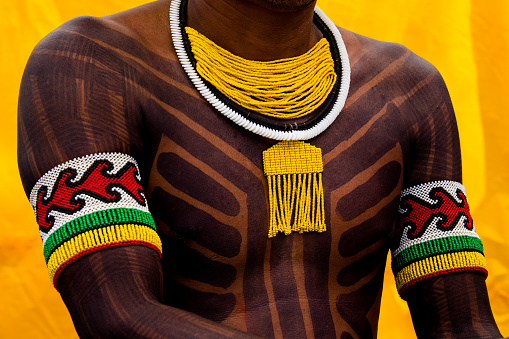 Brasilia, Distrito Federal, Brazil - April, 27, 2017 -detail of body painting and ornaments of indigenous people on a yellow background during the Acampamento Terra Livre event