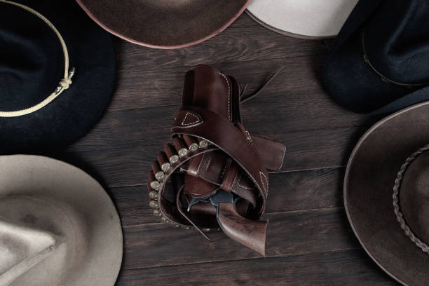 istock Gun with holster and gunbelt with old west hats on table. Top view. 1541357815