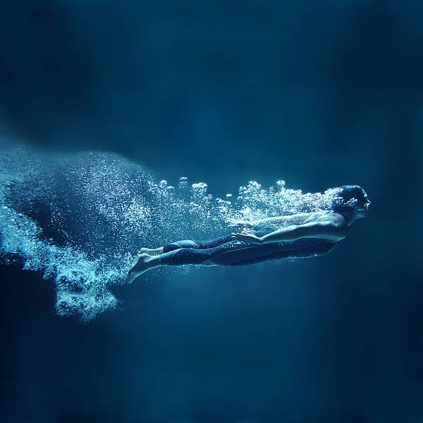 nadador mulher debaixo d'água fluindo sobre fundo azul - bubble swimming pool water underwater - fotografias e filmes do acervo