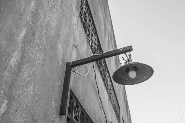 istock Black and White Monochrome Photo of Hanging lightbulbs with canopy or cap protector installed on concrete wall. 1541423256