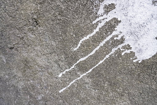 White wall paint drips on the cement concrete wall due to errors and failures in painting. bad unskilled and careless craftsman or painter. Blank empty copy text space.