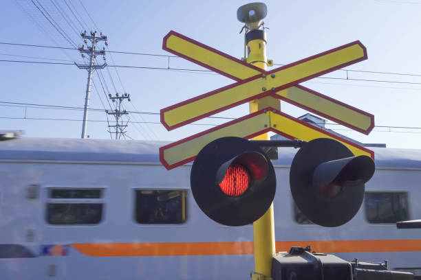 passagem de nível ferroviária é um cruzamento onde uma linha ferroviária atravessa uma estrada, caminho com lâmpada de sinal vermelho. as luzes de travessia do trem estão acesas. - freight train flash - fotografias e filmes do acervo