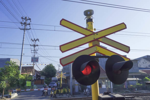 passagem de nível ferroviária é um cruzamento onde uma linha ferroviária atravessa uma estrada, caminho com l�âmpada de sinal vermelho. as luzes de travessia do trem estão acesas. - freight train flash - fotografias e filmes do acervo
