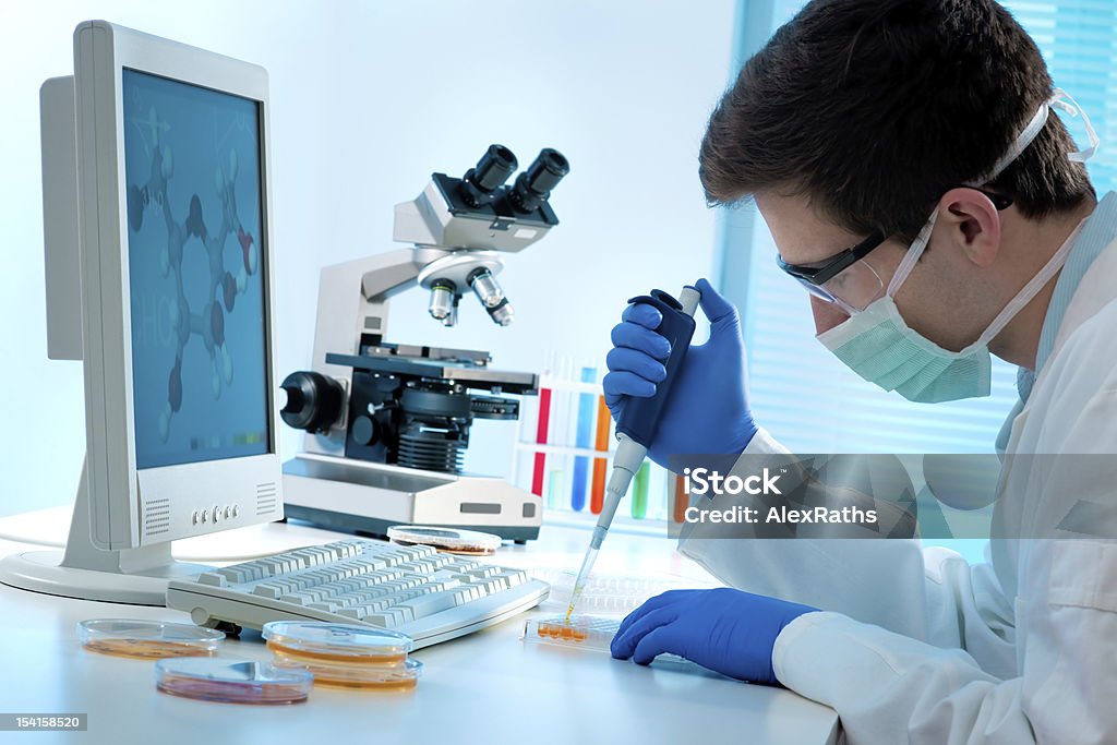 Laboratory technician at work Laboratory technician injecting liquid into a microtiter plate Adult Stock Photo