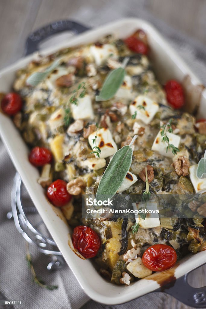 Baked polenta with vegetables Baked Polenta with melted Feta cheese, leek, green peas, cherry tomatoes, sage and thyme. Baked Stock Photo