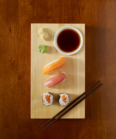 Sushi roll serving with soy sauce, wasabi and ginger on wooden table top