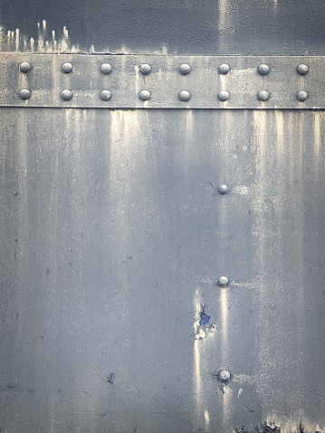 Full fram image of weathered and textured metal surface with rivets