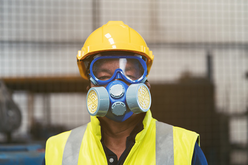 Chemical specialist wear safety uniform and gas mask in dangerous area in the industry factory while standing behind line area barrier red and white colour