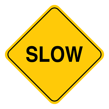 Vector illustration of a black and gold colored road sign with the word slow on it.