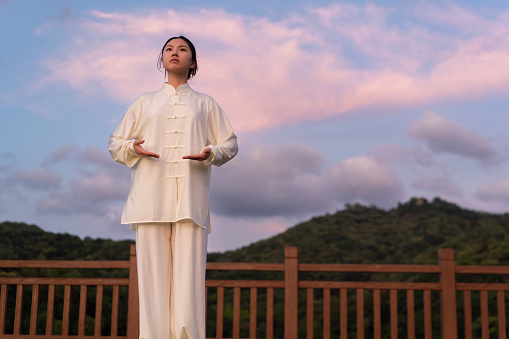 Asian woman is practicing Fitness exercise tai chi in the park.