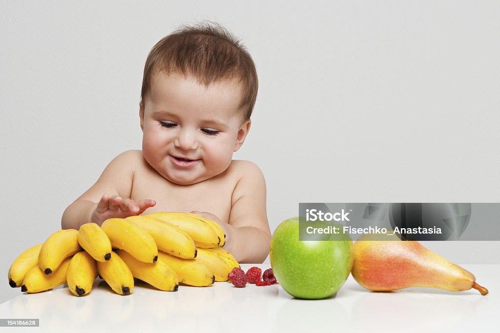 Happy baby with fruits Happy baby boy indoor portrait with fruits on the table. Healthy eating concept. 6-11 Months Stock Photo