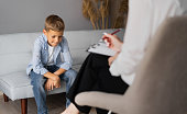 Professional child psychologist working with a schoolboy in a bright office. Children's mental therapy